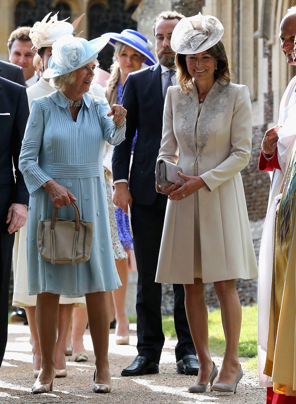 Camilla, Duchess of Cornwall wears a light blue long-sleeved dress with a matching wide-brimmed hat and nude accessories while Kate’s mother Carole Middleton wears a cream-coloured coat with grey embroidery with a matching fascinator.