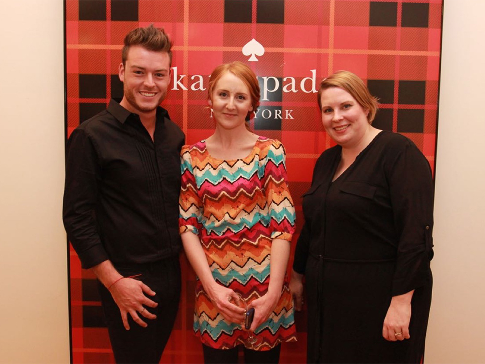 A guest poses with T Galleria by DFS Product Sales Manager Krista Van Op Stal and T Galleria by DFS General Manager Carly Robertson at the Kate Spade boutique opening