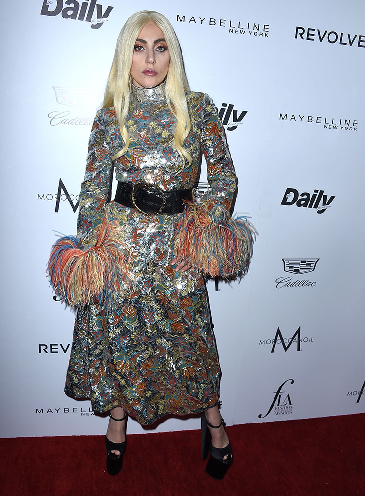 Lady Gaga shows off her fashion prowess in a colourful sequin and feather dress on the red carpet before she accepted the Editor of the Year award.