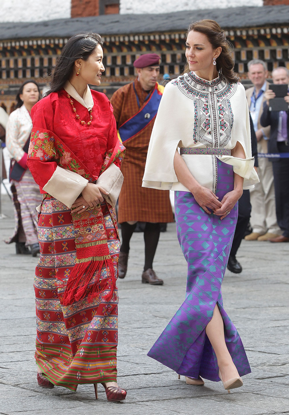 The Duchess of Cambridge walks with HM Jetsun Pema Wangchuck in front of monks in the Tashichhodzong (fortress) in Bhutan.