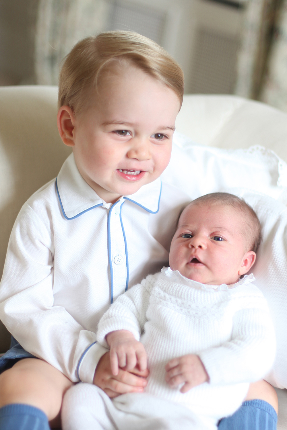 George cuddles up to his new sister, Princess Charlotte, at the family's country home in Norfolk in mid-May 2015.