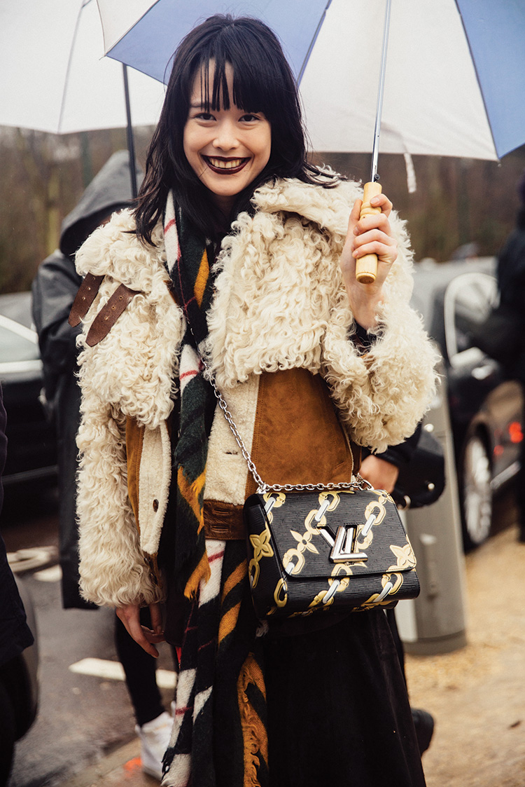 Mae Mei Lapres wears a shearling jacket and a Chain Flower Louis Vuitton twist bag in the rain after the Louis Vuitton show on Day 9 of PFW FW16 on March 09, 2016