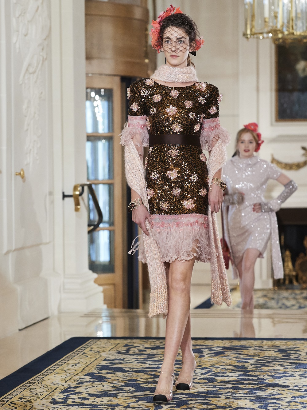 A model wears a dress with sequins and a Chanel fascinator on the runway at Chanel's pre-fall 2017 collection at The Ritz