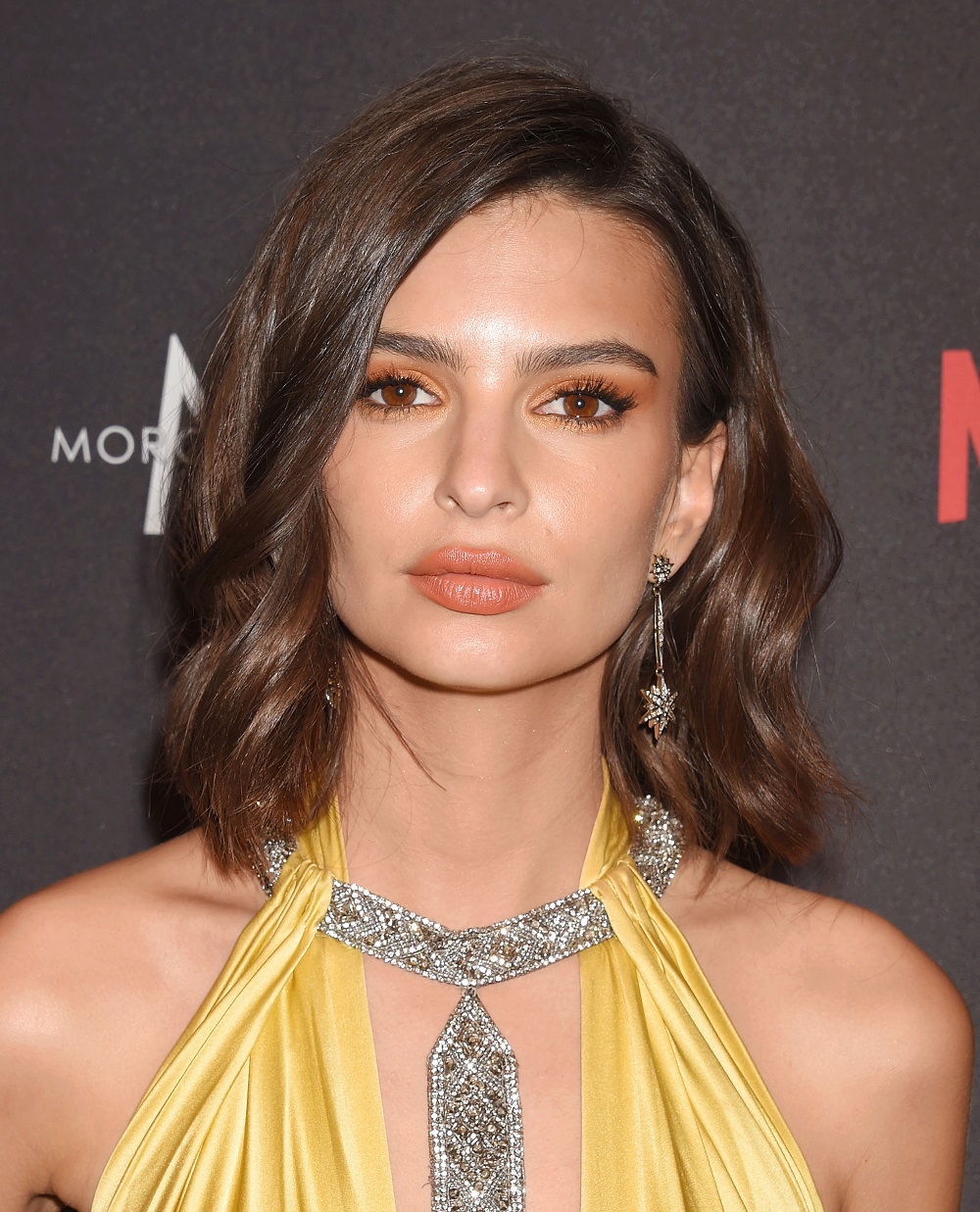 Emily Ratajkowski attends The Weinstein Company and Netflix Golden Globe Party wearing a golden dress with a wavy bob hairstyle.