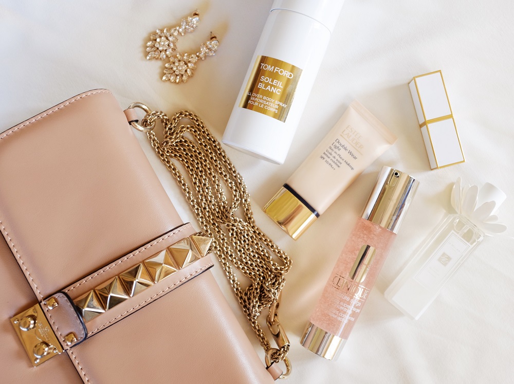 Clare Andrew flat lay of designer handbag and Tom Ford, Estee Lauder beauty products 