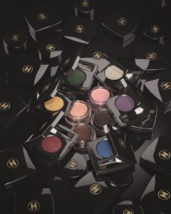 A dark photograph of black makeup with bright Chanel eyeshadows in the centre