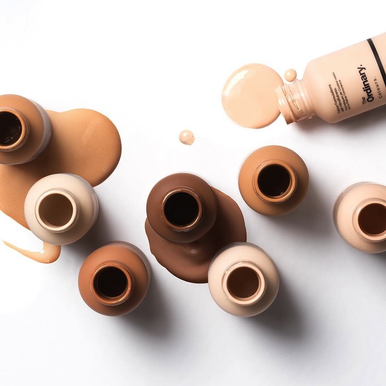 A selection of The Ordinary foundation bottles lie on a white Background 
