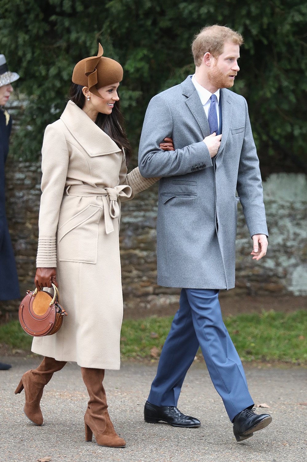 December 25, 2017: Meghan and Prince Harry attend Christmas Day Church service at Church of St Mary Magdalene in King's Lynn, England.Meghan wears a camel Sentaler coat, small brown Chloé bag, Stuart Weitzman boots, Birks diamond snowflake earrings and Philip Treacy hat