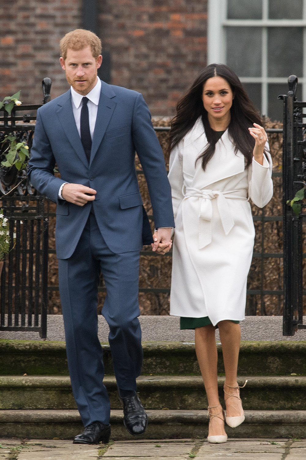 November 27, 2017: During an official photocall to announce her engagementto Prince Harry at The Sunken Gardens at Kensington Palace, Meghan wearsa white wrap coat by Canadian brand Line The Label over an emarld coloured dress with her trusty Aquazzura nude heels that wrap around her ankles.