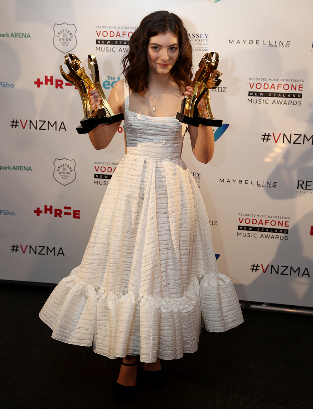 Lorde wears a white dress with stripe detailing and a peplum hem at the VNZMAs.
