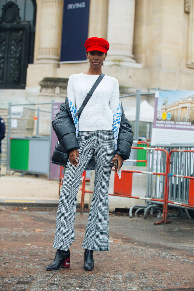 PARIS, FRANCE - JANUARY 23: Model Tami Williams wears a red newsboy cap, a black Adidas bomber jacket off her shoulders, a white sweater, and gray houndstooth pants outside the Chanel show at Grand Palais on January 23, 2018 in Paris, France. (Photo by Melodie Jeng/Getty Images)