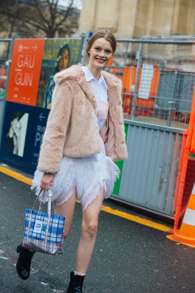 PARIS, FRANCE - JANUARY 23: Model Kris Giskaite wears a light pink fur coat over a white Prada feather-trimmed shirt dress white dress and a plaid Opening Ceremony bag outside the Chanel show at Grand Palais on January 23, 2018 in Paris, France. (Photo by Melodie Jeng/Getty Images)