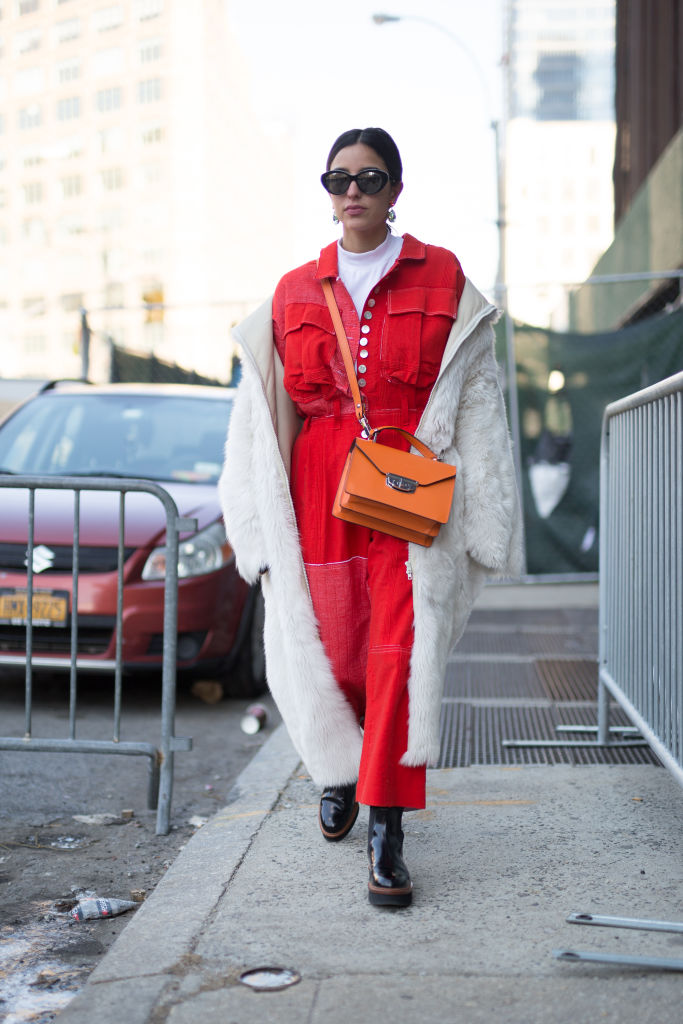 NEW YORK, NY - FEBRUARY 08: A guest is seen on the street attending Colovos and Noon By Noor during New York Fashion Week wearing a red outfit with cream long coat and orange bag on February 8, 2018 in New York City. (Photo by Matthew Sperzel/Getty Images)