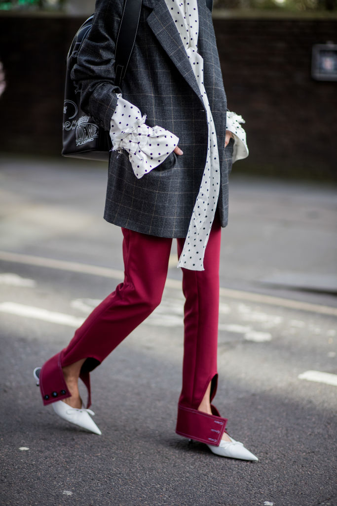 LONDON, ENGLAND - FEBRUARY 17: A guest wearing blouse with wide sleeves, grey blazer, red flared pants with slit, pointed shoes, Loewe backpack seen outside Simone Rocha during London Fashion Week February 2018 on February 17, 2018 in London, England. (Photo by Christian Vierig/Getty Images)