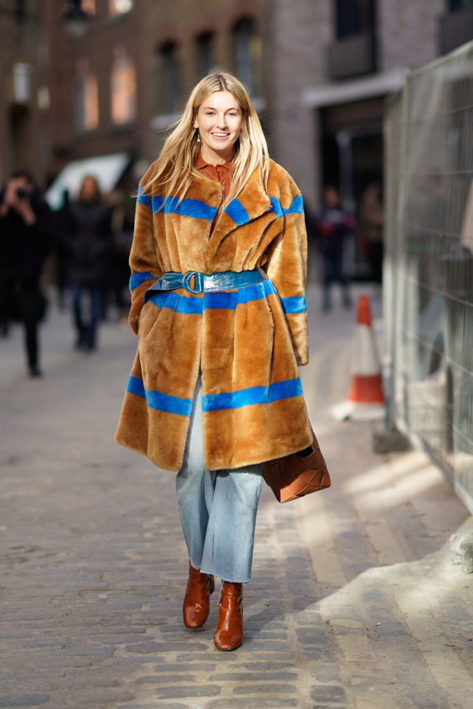 LONDON, ENGLAND - FEBRUARY 17: Camille Charriere wears a brown fluffy coat with blue stripes, blue jeans, a brown shirt, a blue belt,, brown boots, during London Fashion Week February 2018 on February 17, 2018 in London, England. (Photo by Edward Berthelot/Getty Images)