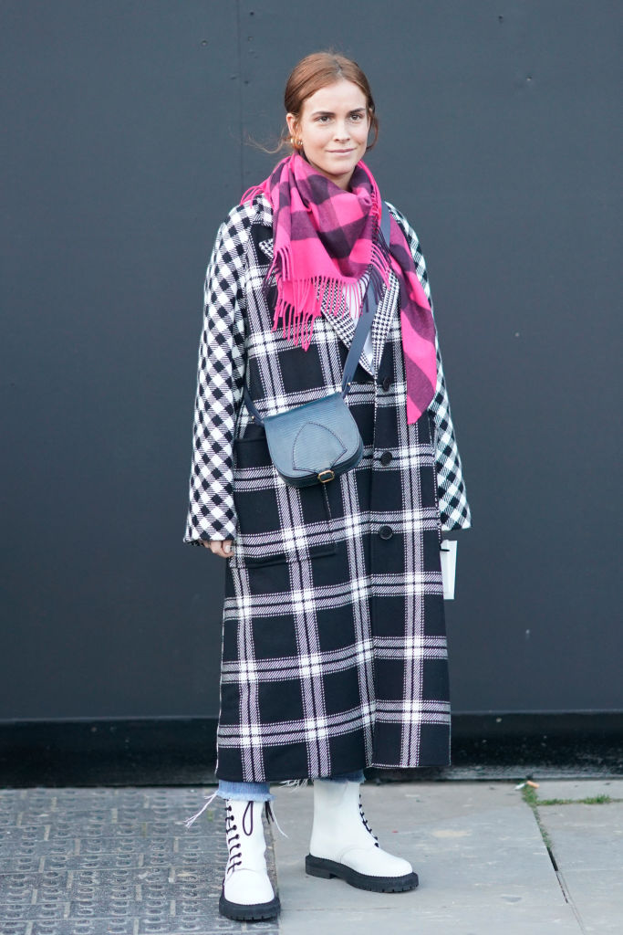 LONDON, ENGLAND - FEBRUARY 17: A guest wears a pink scarf, a balck bag, a checked coat, white boots, during London Fashion Week February 2018 on February 17, 2018 in London, England. (Photo by Edward Berthelot/Getty Images)