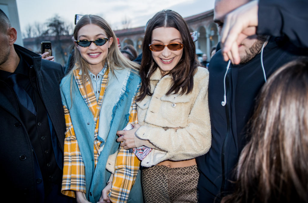 MILAN, ITALY - FEBRUARY 21: Gigi Hadid wearing denim vest, tartan jacket, denim button shirt and Bella Hadid wearing cropped top and jacket, silk pants seen outside Alberta Ferretti during Milan Fashion Week Fall/Winter 2018/19 on February 21, 2018 in Milan, Italy. (Photo by Christian Vierig/Getty Images)