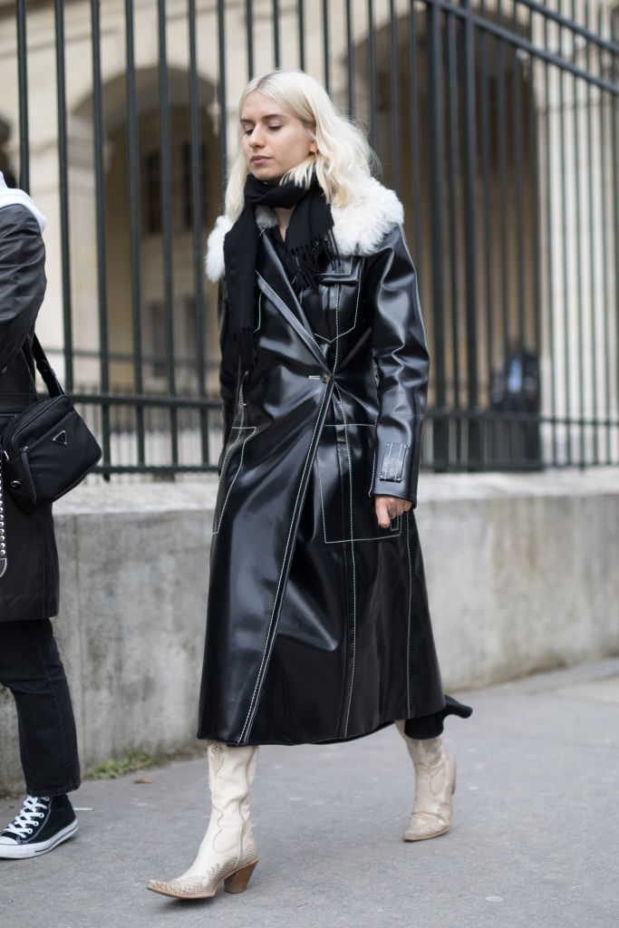 PARIS, FRANCE - MARCH 03: A guest is seen on the street attending Noir Kei Ninomiya during Paris Women's Fashion Week A/W 2018 wearing a long black leather coat with beige boots on March 3, 2018 in Paris, France. (Photo by Matthew Sperzel/Getty Images)