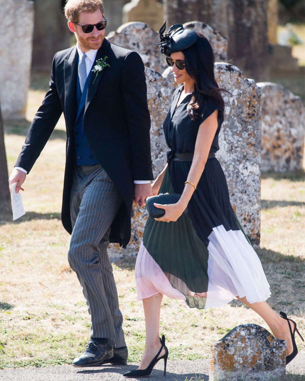 August 4, 2018: No boatneck for the birthday girl, today! Meghan, Duchess of Sussex sees in her 37th year by attending the wedding of Prince Harry’s childhood friend wearing a dress by Club Monaco featuring a colour-blocked skirt, cap sleeve and button-up silhouette. Meghan accessorised with a black snakeskin clutch, go-to Aquazzura heels and a black Phillip Treacy fascinator.