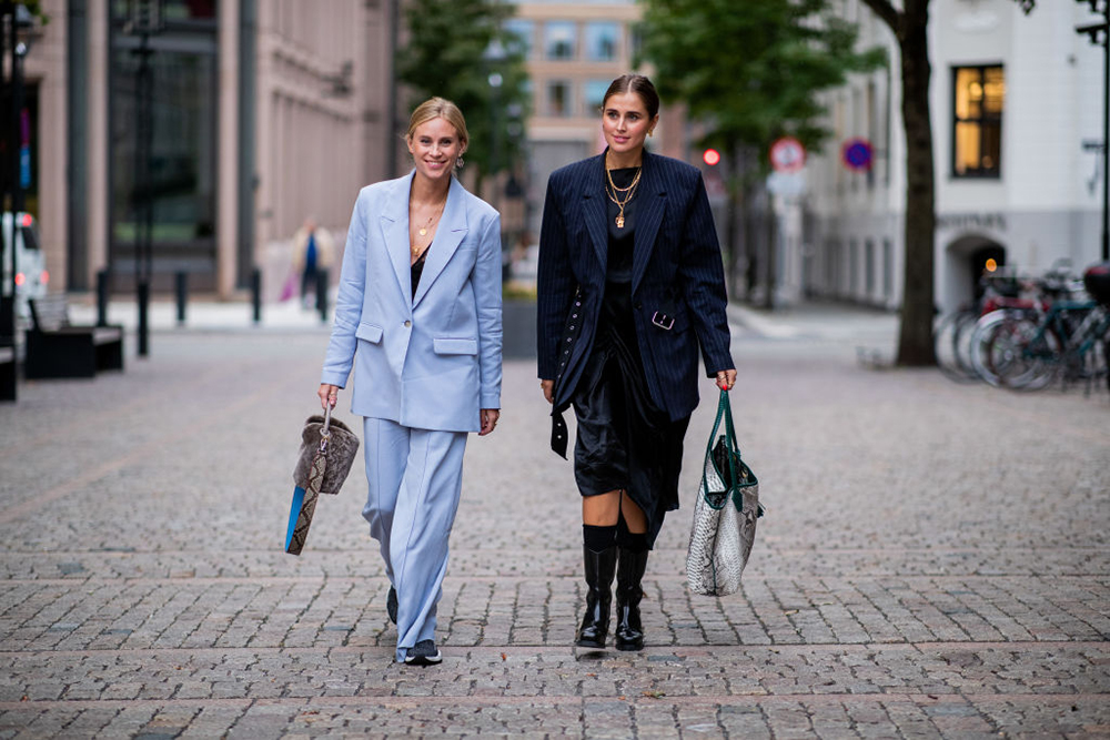 OSLO, NORWAY - AUGUST 15: Tine Andrea wearing blue suit and Darja Barannik wearing oversized blazer jacket, boots, asymmetrical skirt seen outside FWSS during Oslo Runway SS19 on August 15, 2018 in Oslo, Norway. (Photo by Christian Vierig/Getty Images)