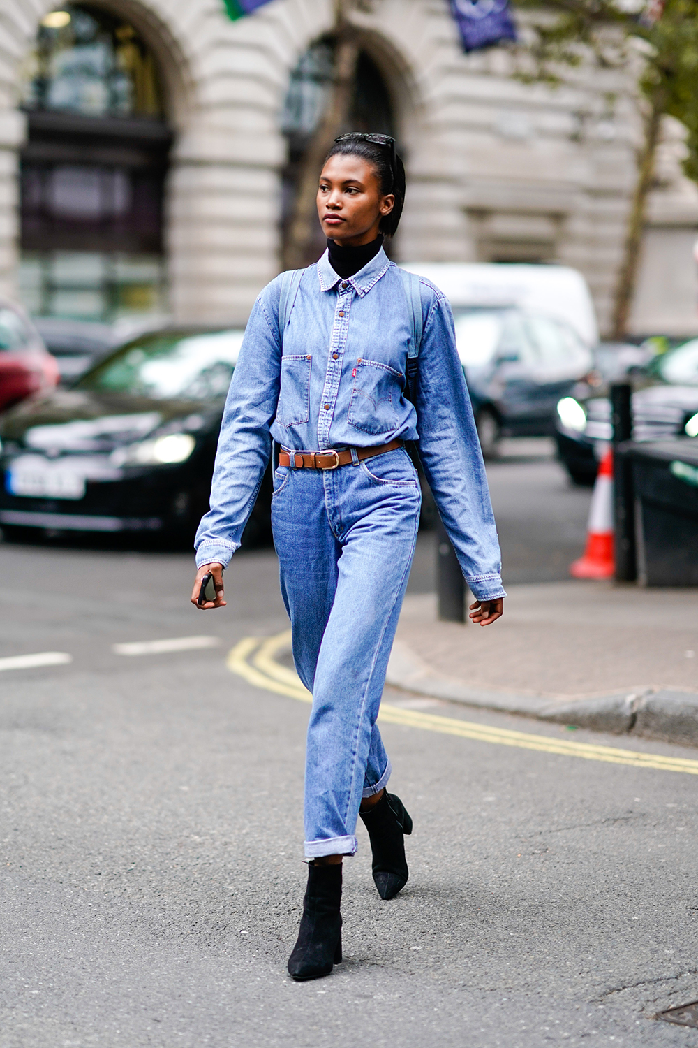 A model wears a blue denim shirt, a brown leather belt, cropped pants, black shoes, during London Fashion Week September 2018 on September 14, 2018 in London, England. (Photo by Edward Berthelot/Getty Images)