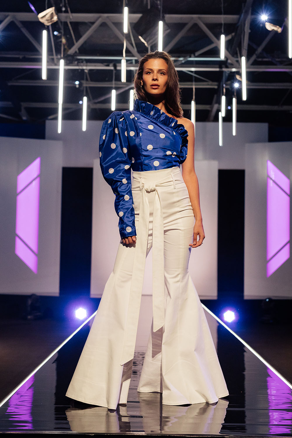 Caitlin An ‘80s dress in a bright blue high shine fabric with large white polka dots and puffy sleeves becomes the hero in a one-sleeved statement blouse with a leg of mutton sleeve and pleating through the neckline. Caitlin also designed very fitted white high-waist trousers with a flare detail at the base to bring out the polka dot even further. Judges’ comments: Georgia: “Clearly Julia loved it. It fits you so well.” Sally-Ann: “I wrote down Bianca Jagger. I can see this on an international runway. I just love it” Robert: “I wrote down 90s Madonna. The pants are made exceptionally well.” Benny: “Loved it to pieces. This is my favourite before and after.”