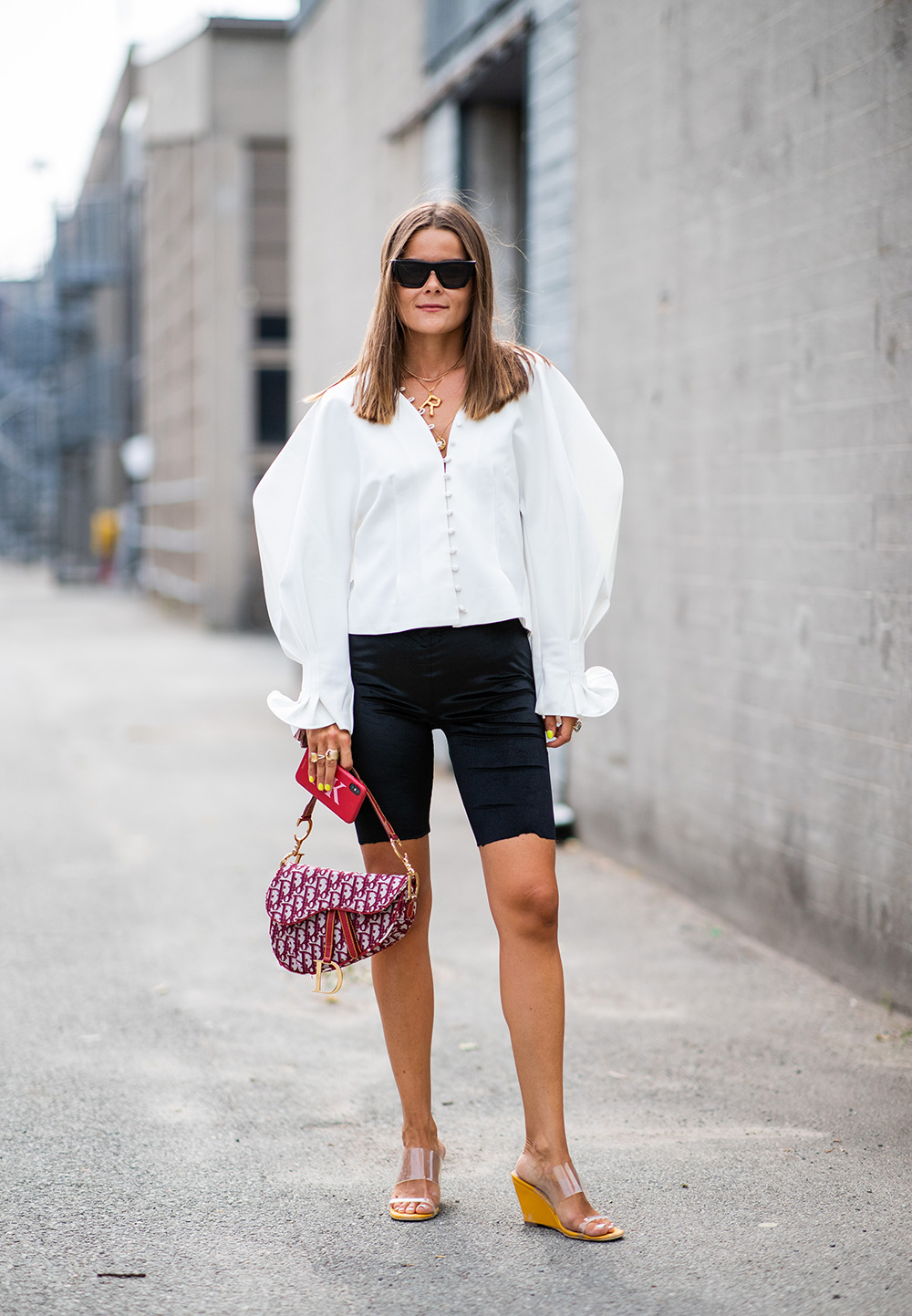 10 ways to wear the bike pant trend outside of the gym | COPENHAGEN, DENMARK - AUGUST 08: A guest wearing white blouse, Dior saddle bag, cycle pants is seen outside J.Lindeberg during the Copenhagen Fashion Week Spring/Summer 2019 on August 8, 2018 in Copenhagen, Denmark. (Photo by Christian Vierig/Getty Images)