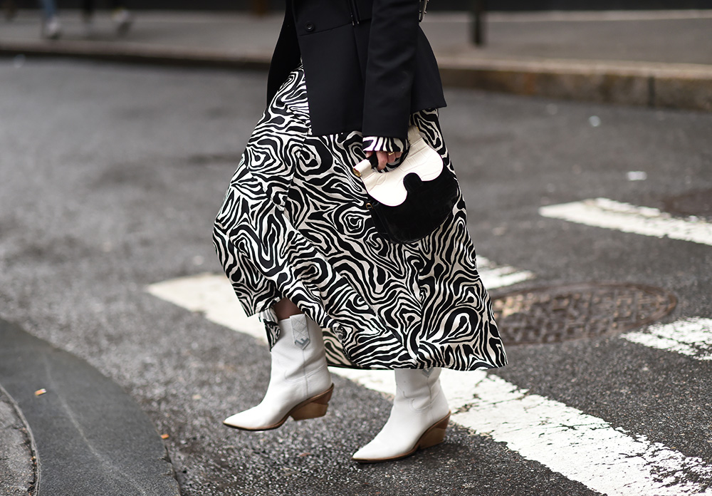 NEW YORK, NEW YORK - FEBRUARY 08: A guest is seen wearing a black and white skirt, black and white bag and white leather boots outside the Kate Spade show during New York Fashion Week: Fall/Winter 2019 on February 08, 2019 in New York City. (Photo by Daniel Zuchnik/Getty Images)