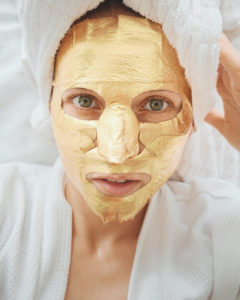 Woman wearing gold foil sheet mask