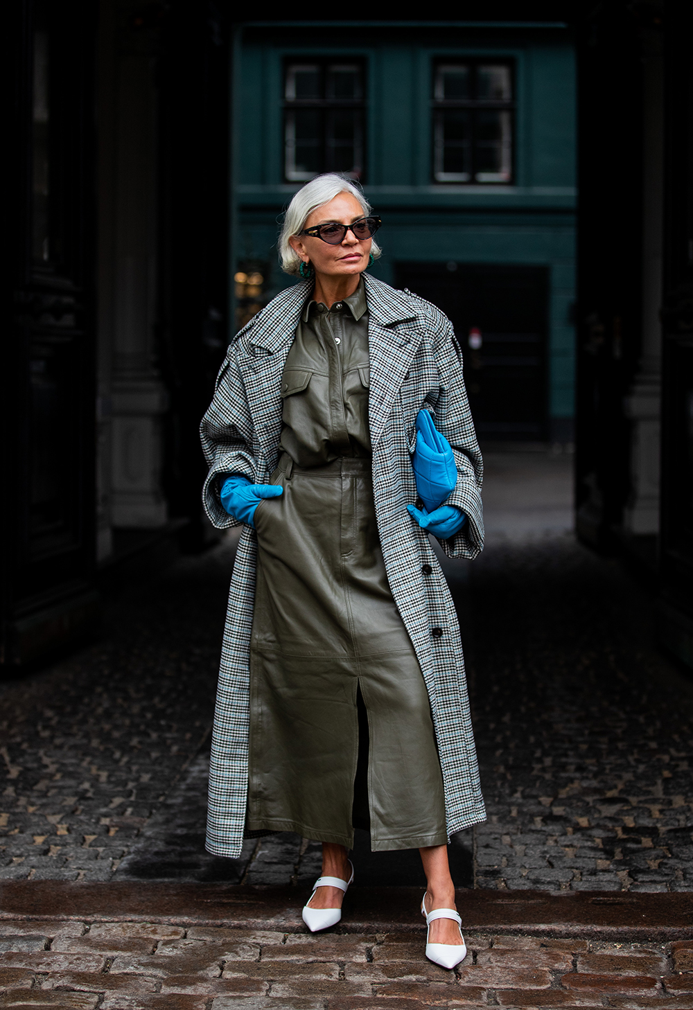 COPENHAGEN, DENMARK - JANUARY 28: A guest is seen wearing olive skirt, button shirt, blue gloves and bag, grey checkered coat outside Gestuz on Day 1 during Copenhagen Fashion Week Autumn/Winter 2020 on January 28, 2020 in Copenhagen, Denmark. (Photo by Christian Vierig/Getty Images)