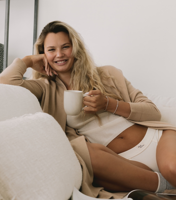 Image of Juliette Perkins postpartum sitting on her couch relaxing with a cuppa.