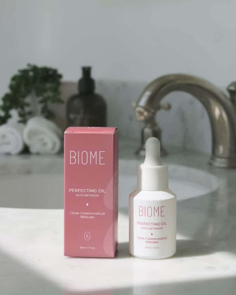 ebecca Spencer, founder of Biome Skin and Beauty, smiling in her skincare clinic, showcasing her Biome Perfecting Oil.