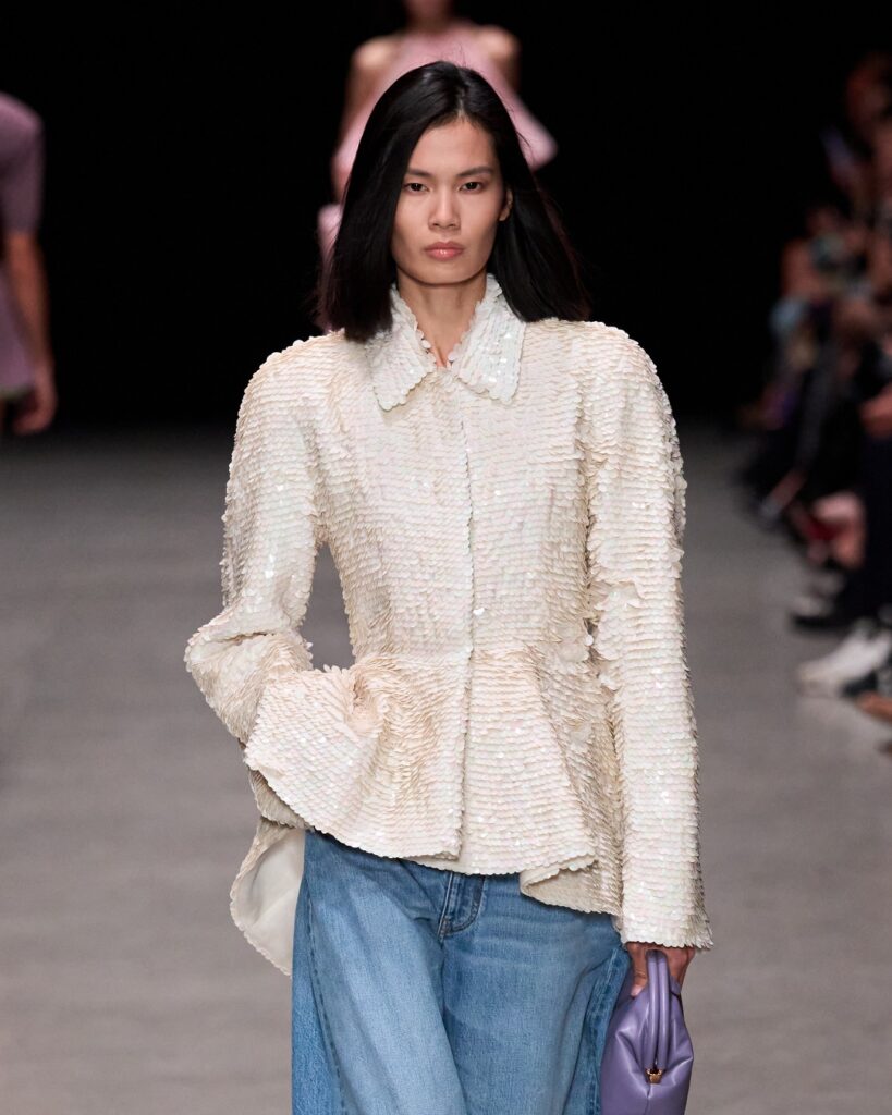 Model wearing a cream tweed peplum jacket with jeans, styled. Stella McCartney